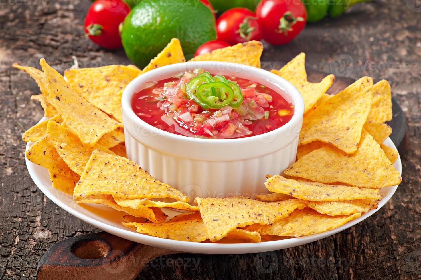 Mexican nacho chips and salsa dip in  bowl on  wooden background photo