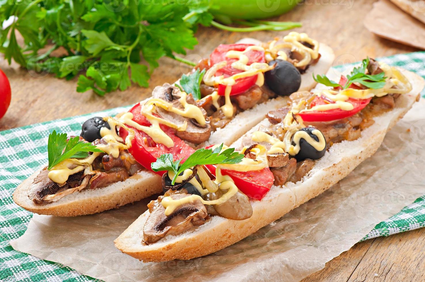 Baguette stuffed with veal and mushrooms with tomatoes and cheese photo