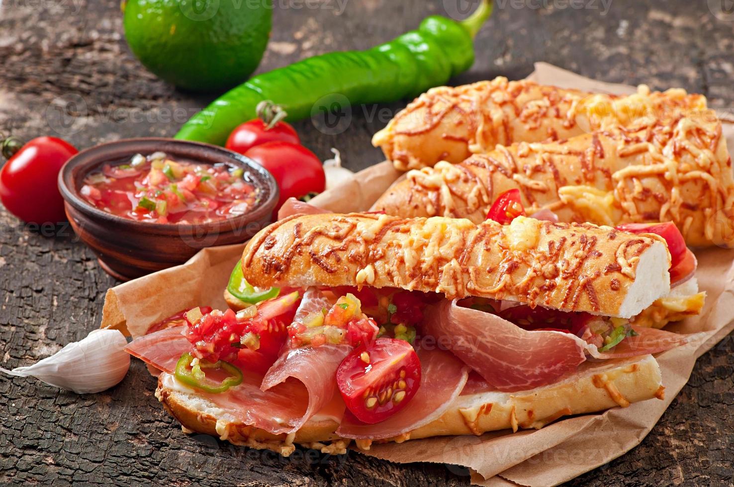 Salsa dip in bowl of bread and cheese sticks on wooden background photo
