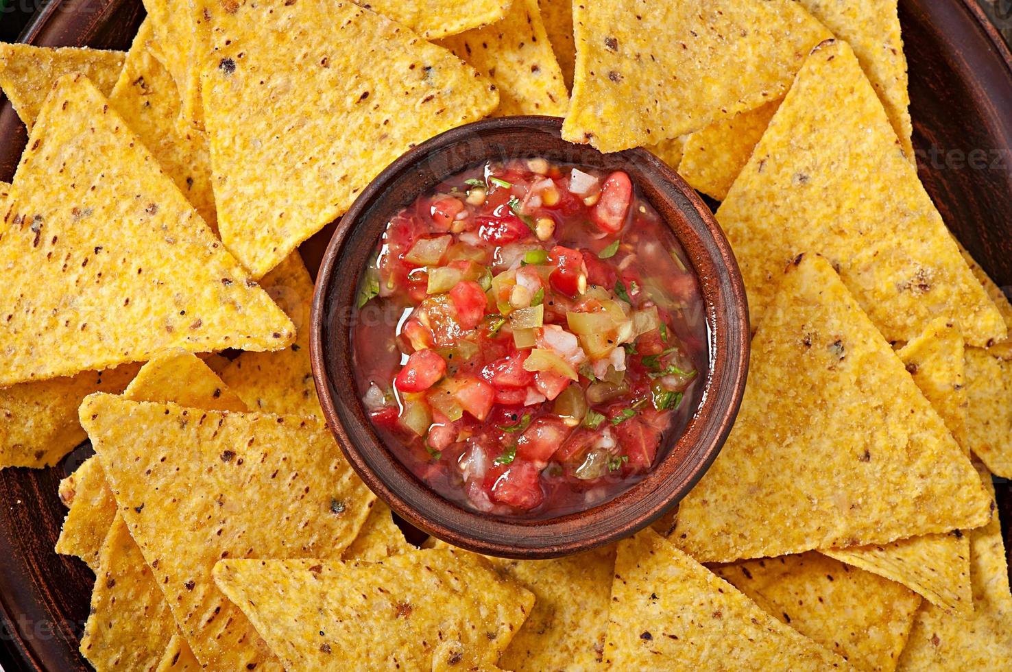 Mexican nacho chips and salsa dip in  bowl on  wooden background photo