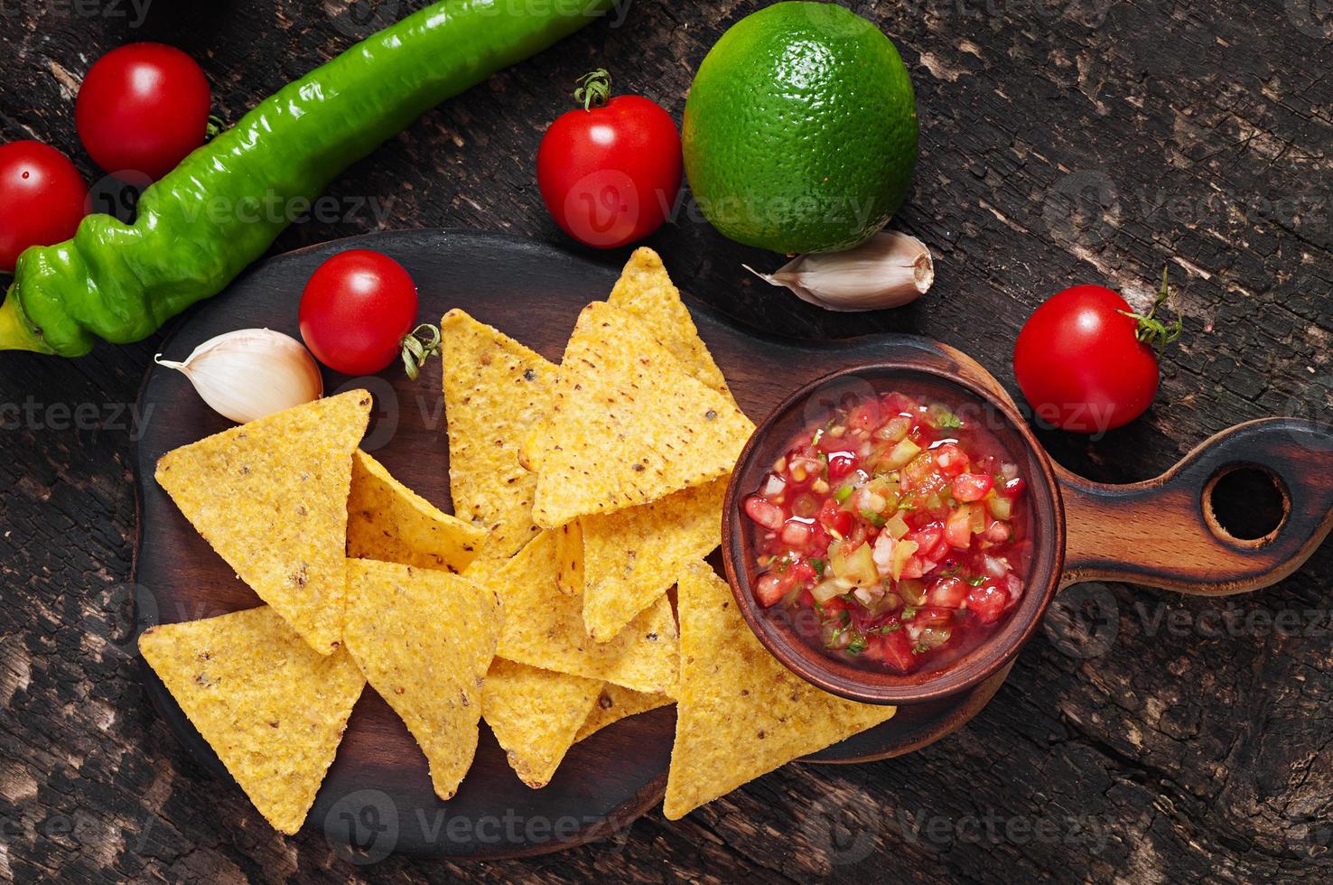 Mexican nacho chips and salsa dip in  bowl on  wooden background photo