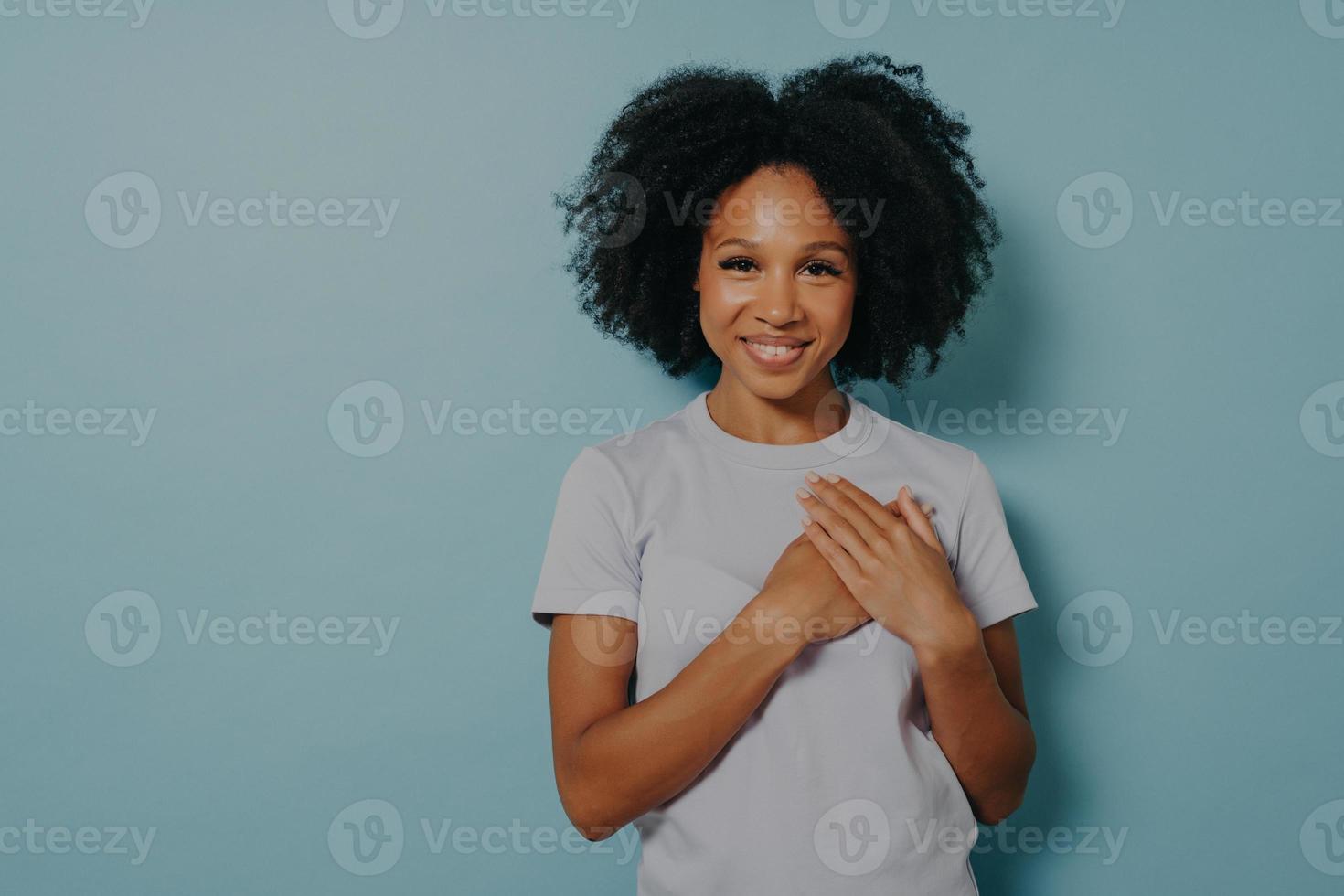 agradecida mujer negra feliz tomándose de la mano en el pecho, dama africana satisfecha expresando amor de corazón foto