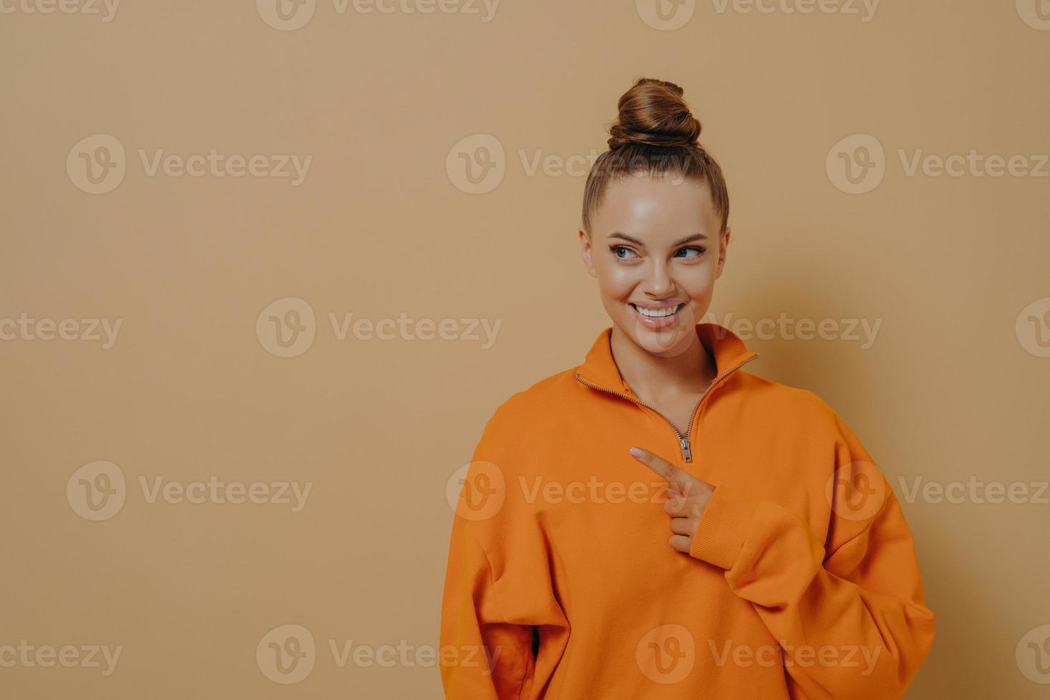 Positive smiling girl indicating pointing with forefinger to side, showing place for advertisement photo