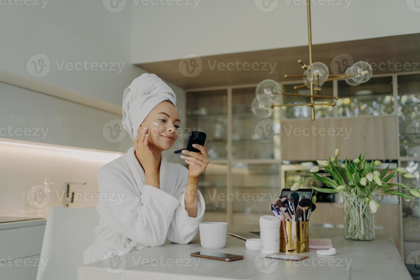 Happy healthy woman in bathrobe taking care of her skin after taking shower or bath at home photo