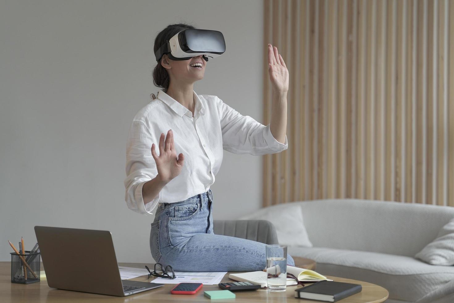 Businesswoman in elegant formal clothes sitting in office and using VR technologies at work photo
