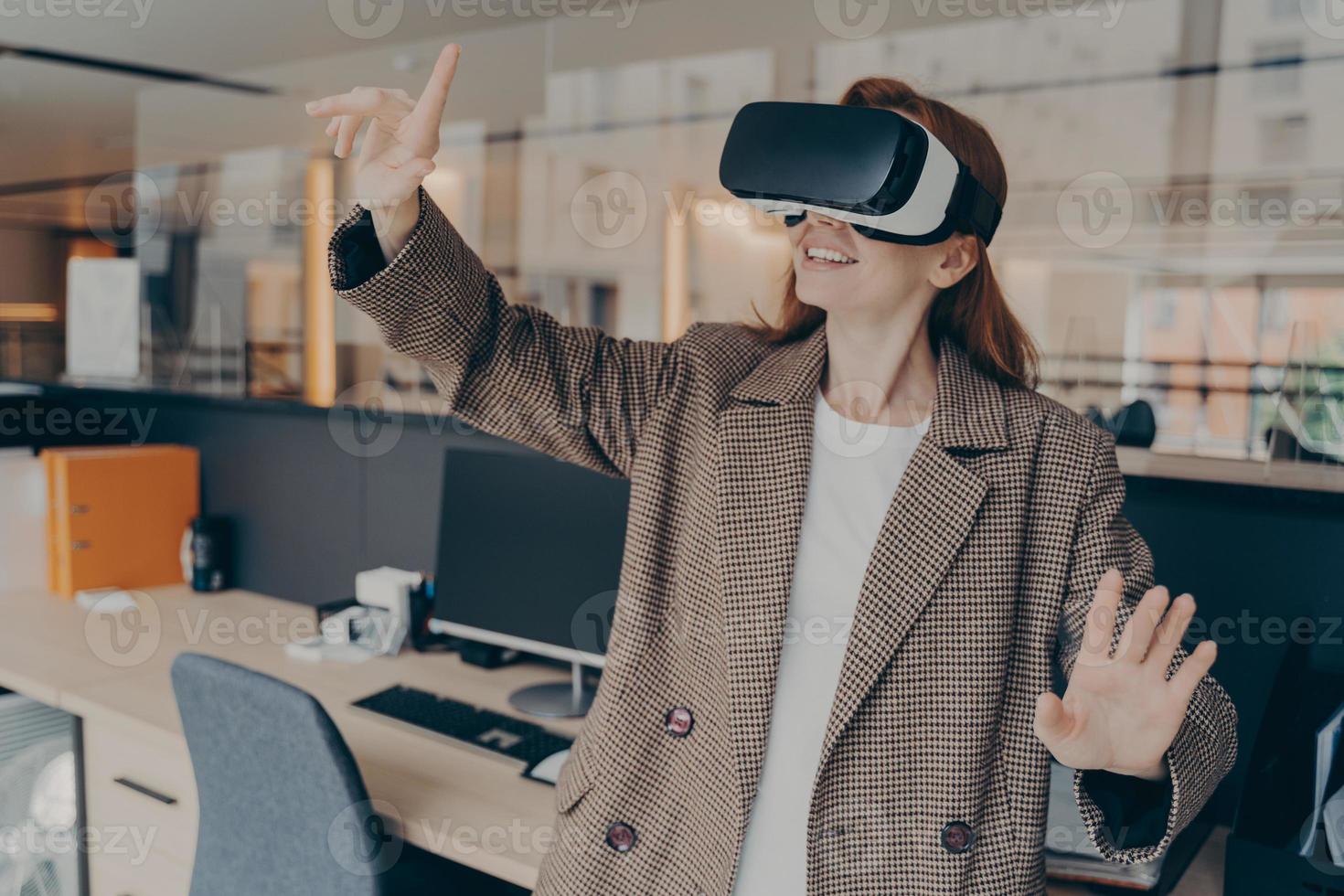 Happy female office worker in VR headset enjoying virtual reality game on her break photo