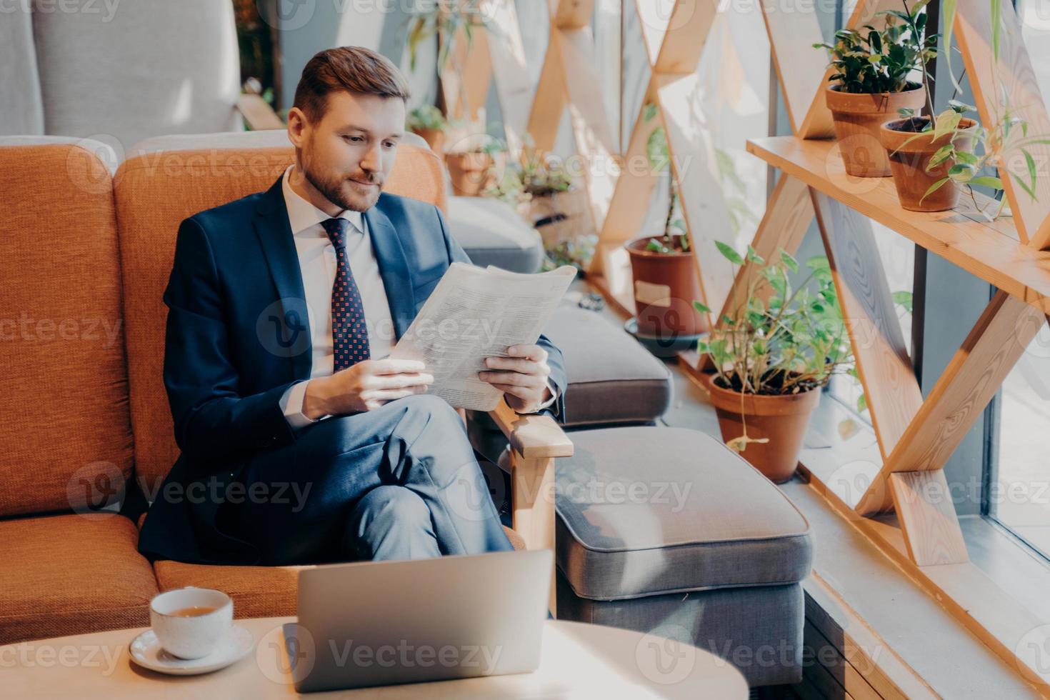 Busy corporate employee reading newspaper in cafe photo