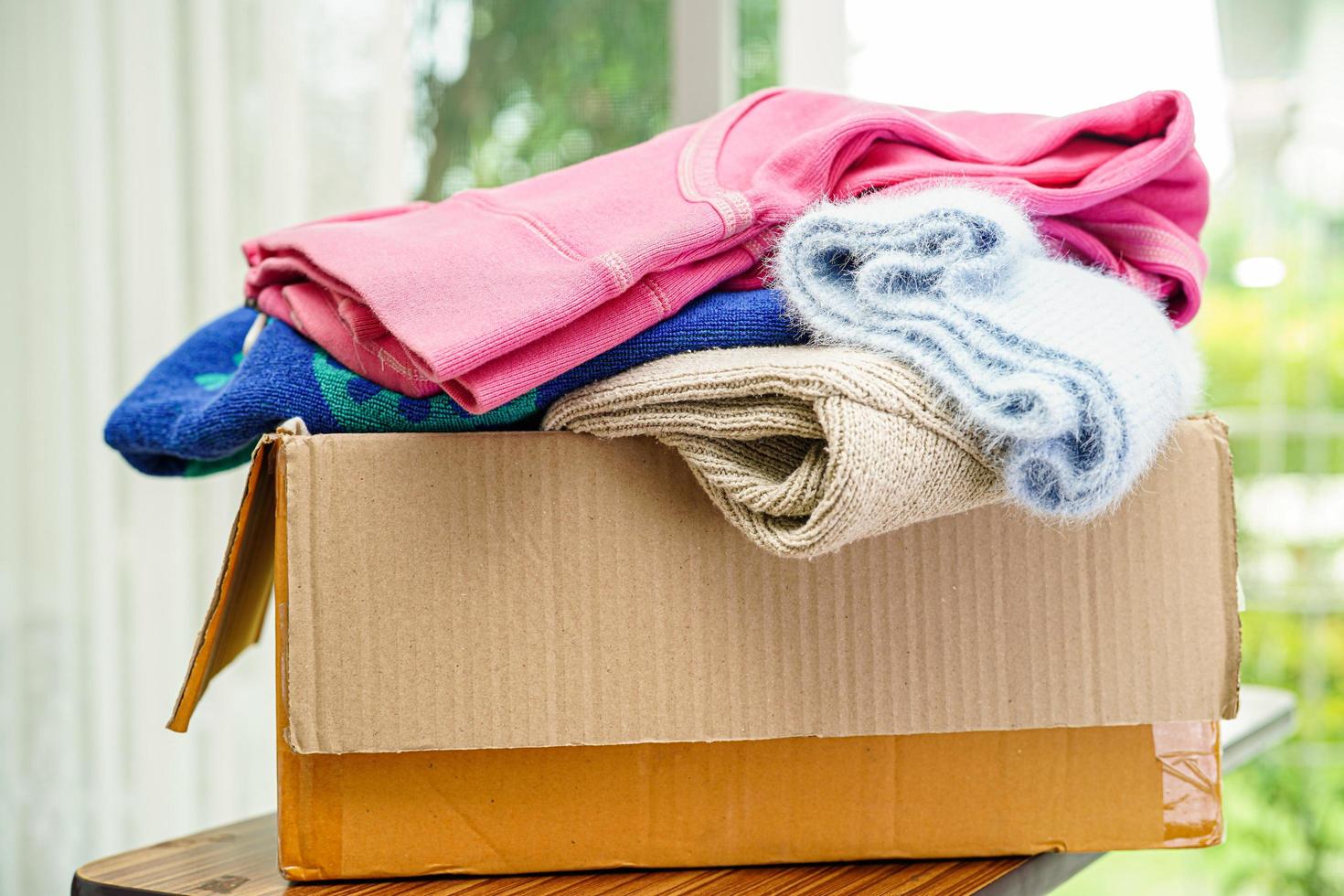Clothes donations in cardboard box for volunteer. photo