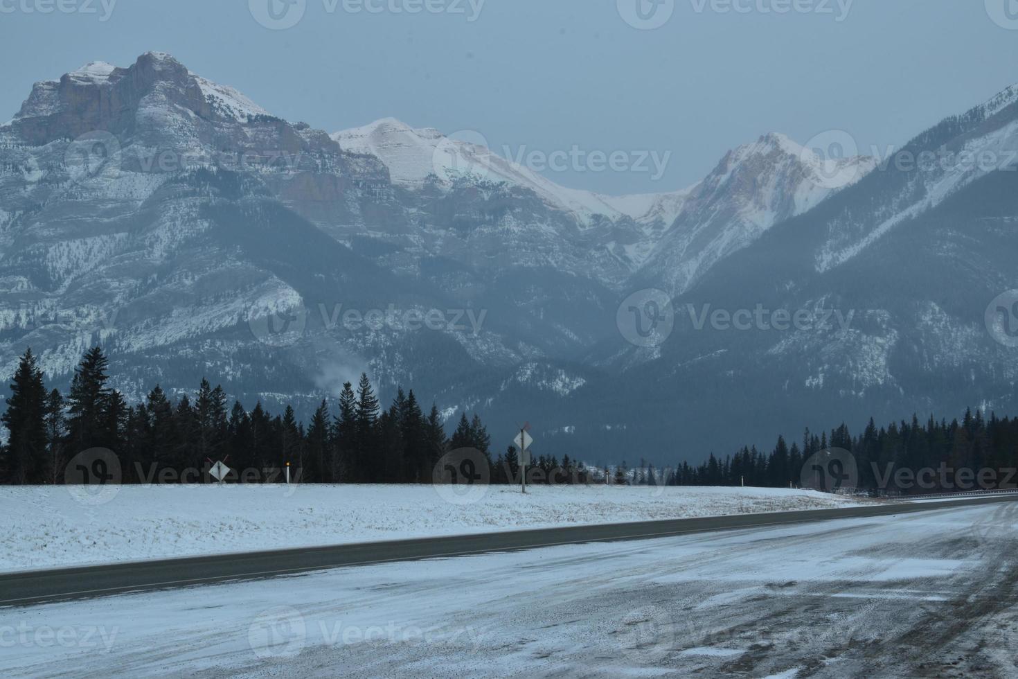 Snow covered highway with mountains in the background photo