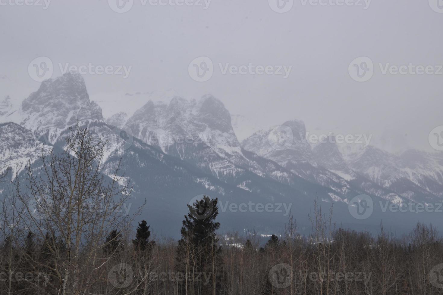 montañas rocosas cubiertas de nieve con cielo gris nebuloso foto