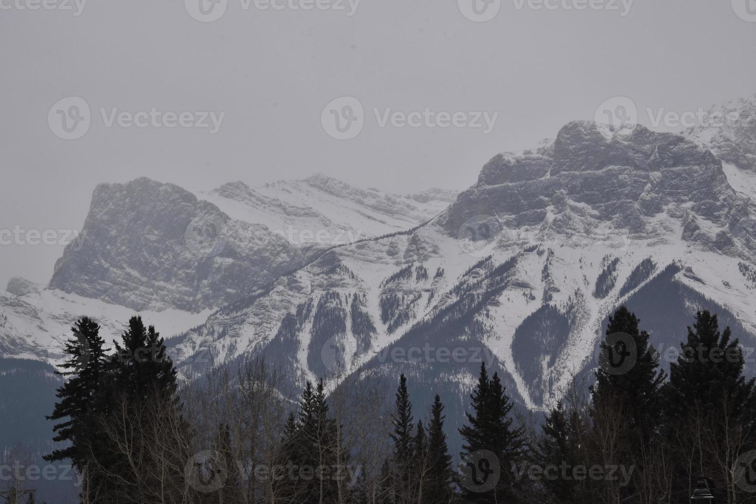 montañas rocosas cubiertas de nieve con cielo gris nebuloso foto