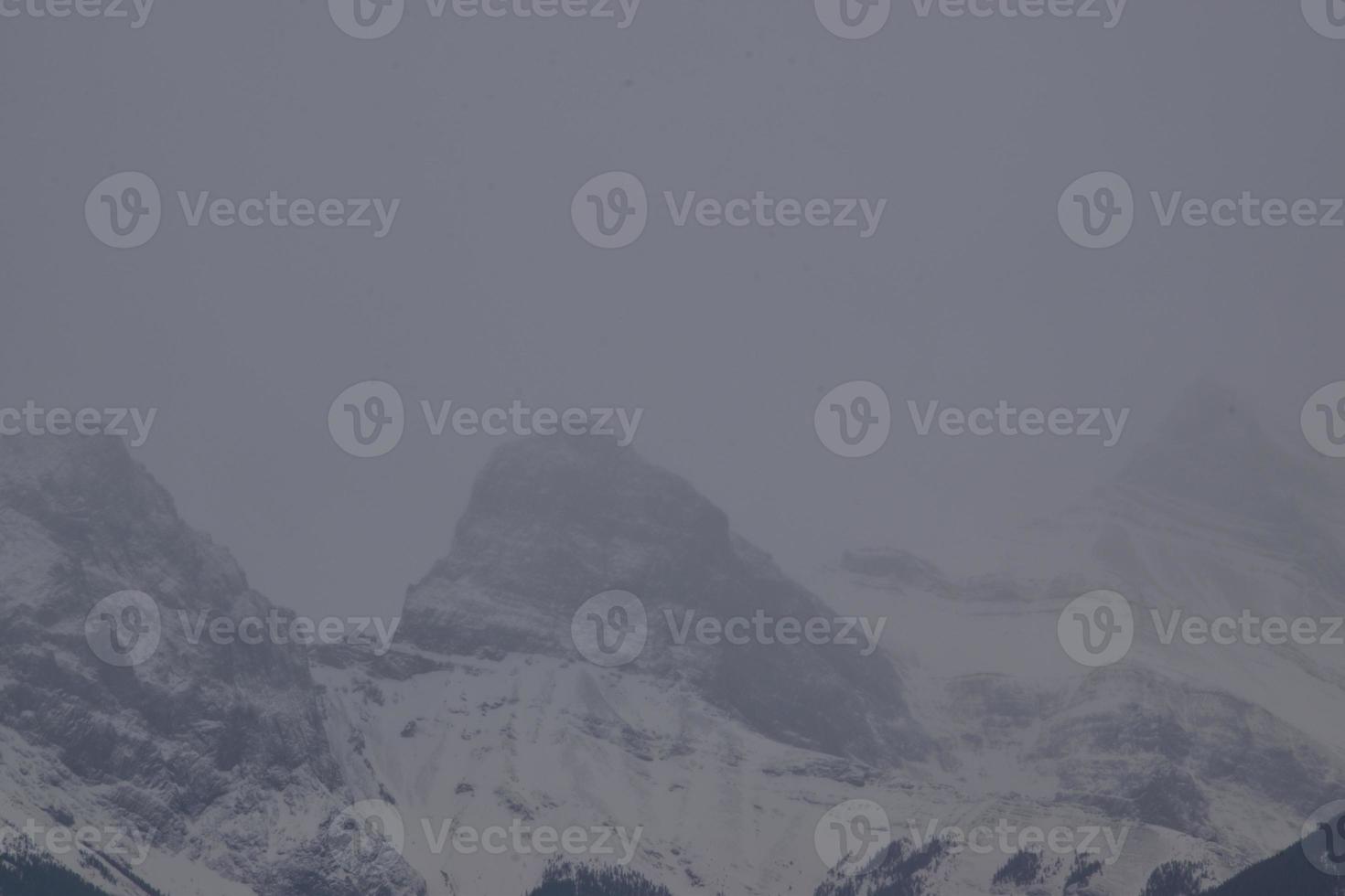 Snow Covered Rocky Mountains with Hazy Grey Sky photo