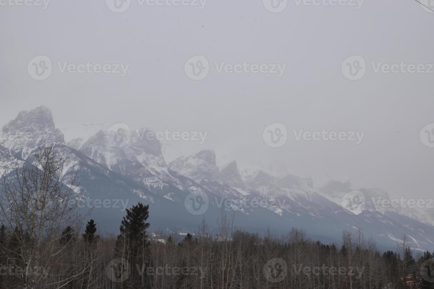 Snow Covered Rocky Mountains with Hazy Grey Sky photo