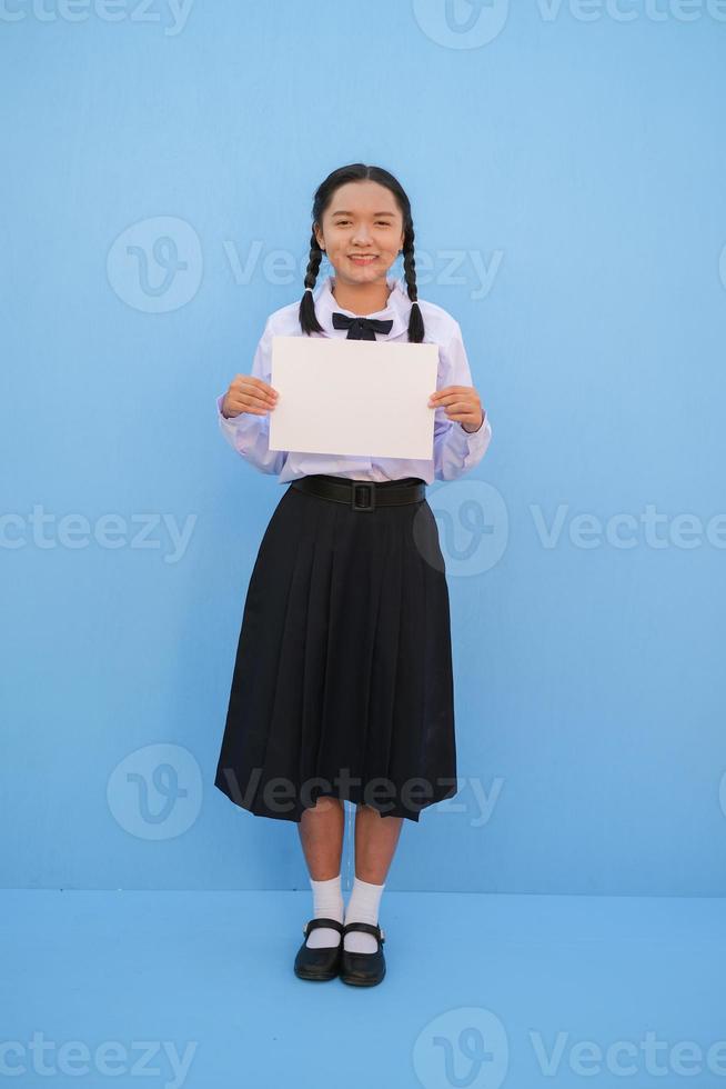 niña de la escuela con cartelera sobre fondo azul. foto