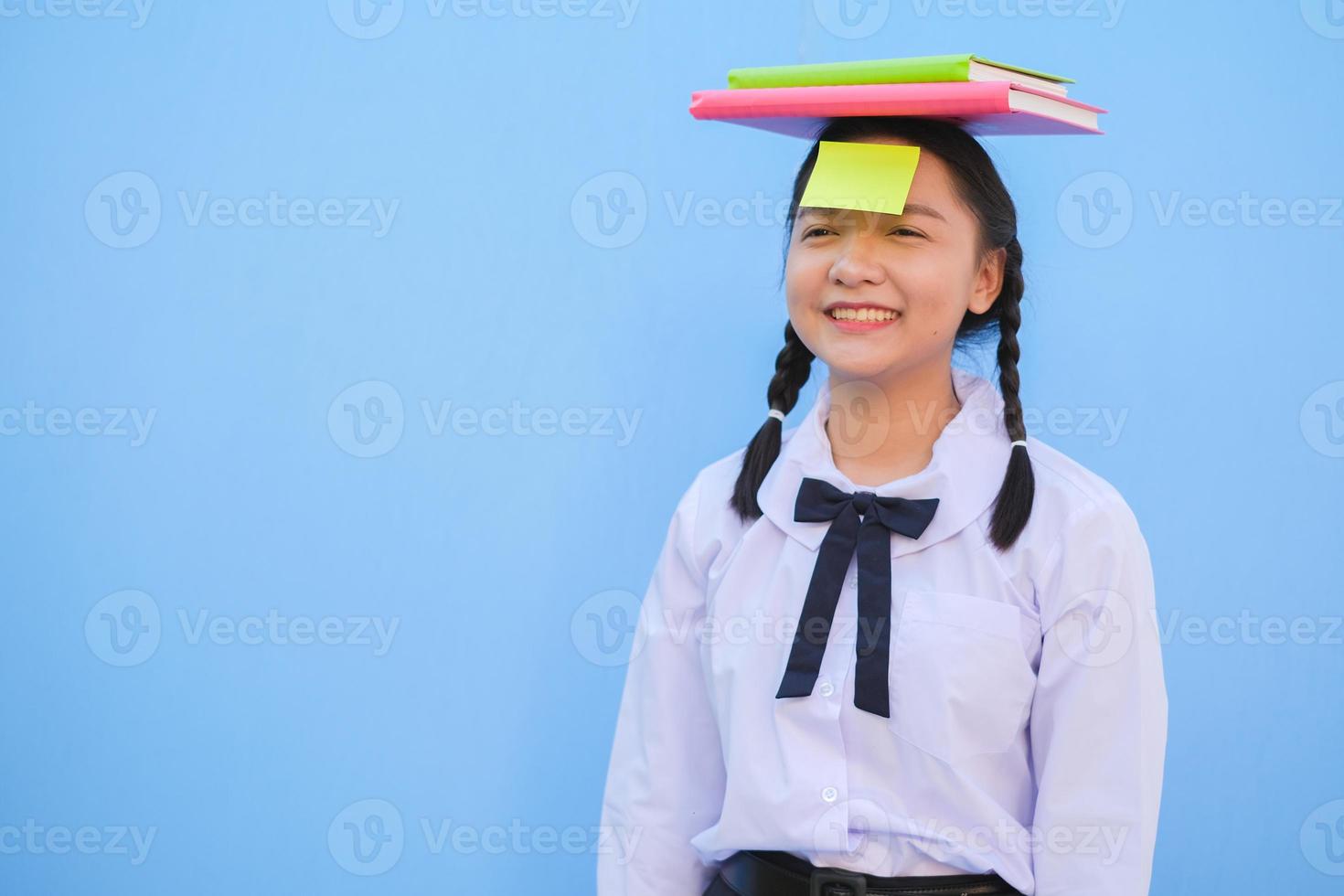 Student with book and small note paper on blue background. photo