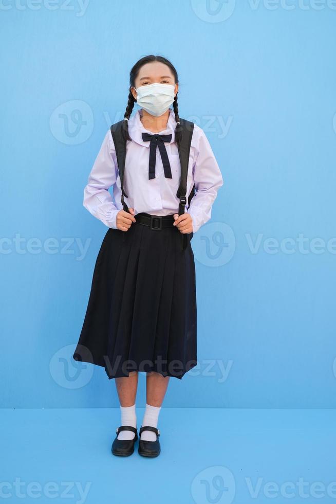 School girl wear mask on blue background,Back to school. photo