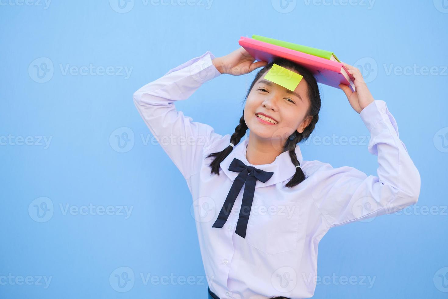 Student with book and small note paper on blue background. photo