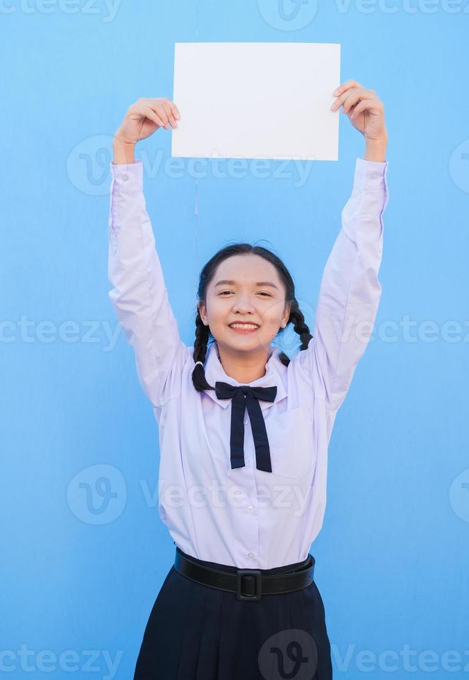 niña de la escuela con cartelera sobre fondo azul. foto