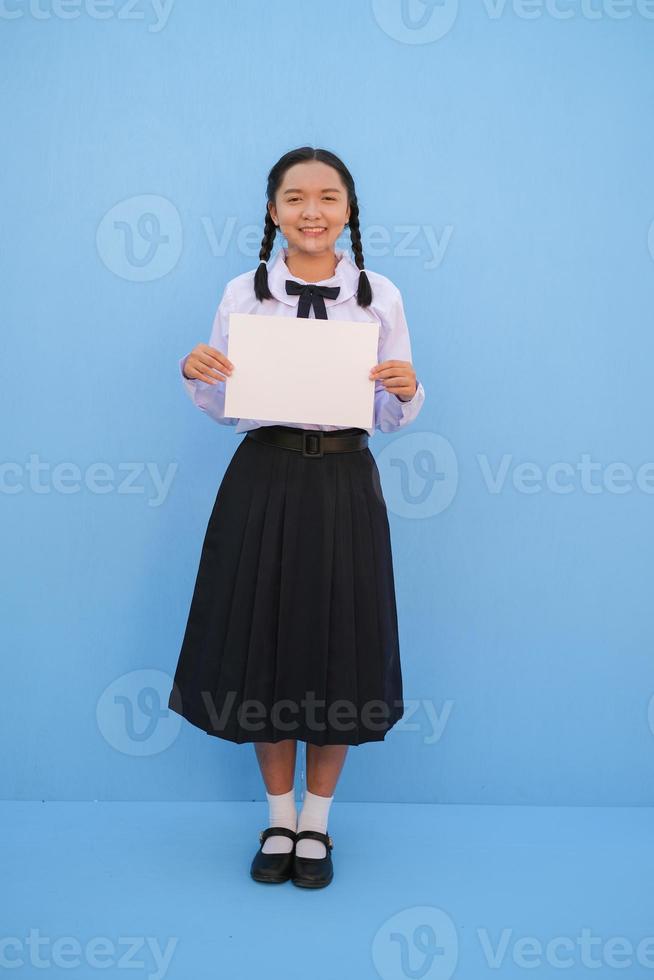 niña de la escuela con cartelera sobre fondo azul. foto