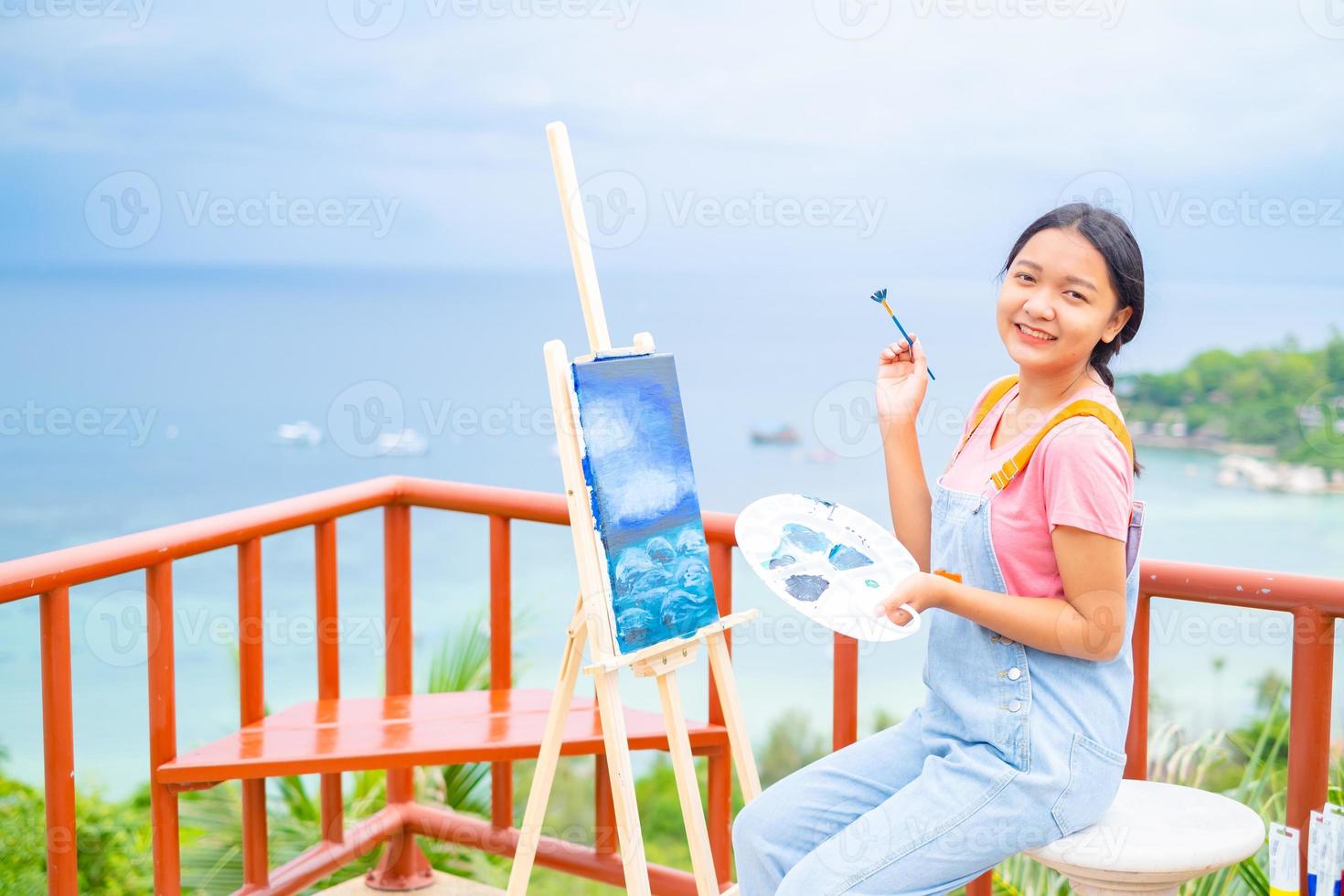 niña usando un dibujo de pincel sobre papel de lienzo, en una hermosa vista del paisaje en koh tao, tailandia. foto