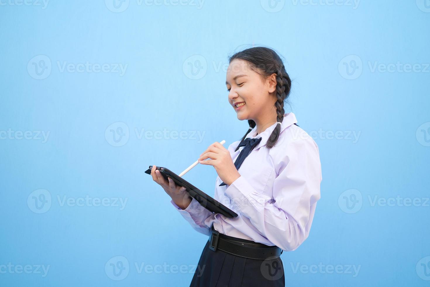 School girl holding tablet on blue background. photo