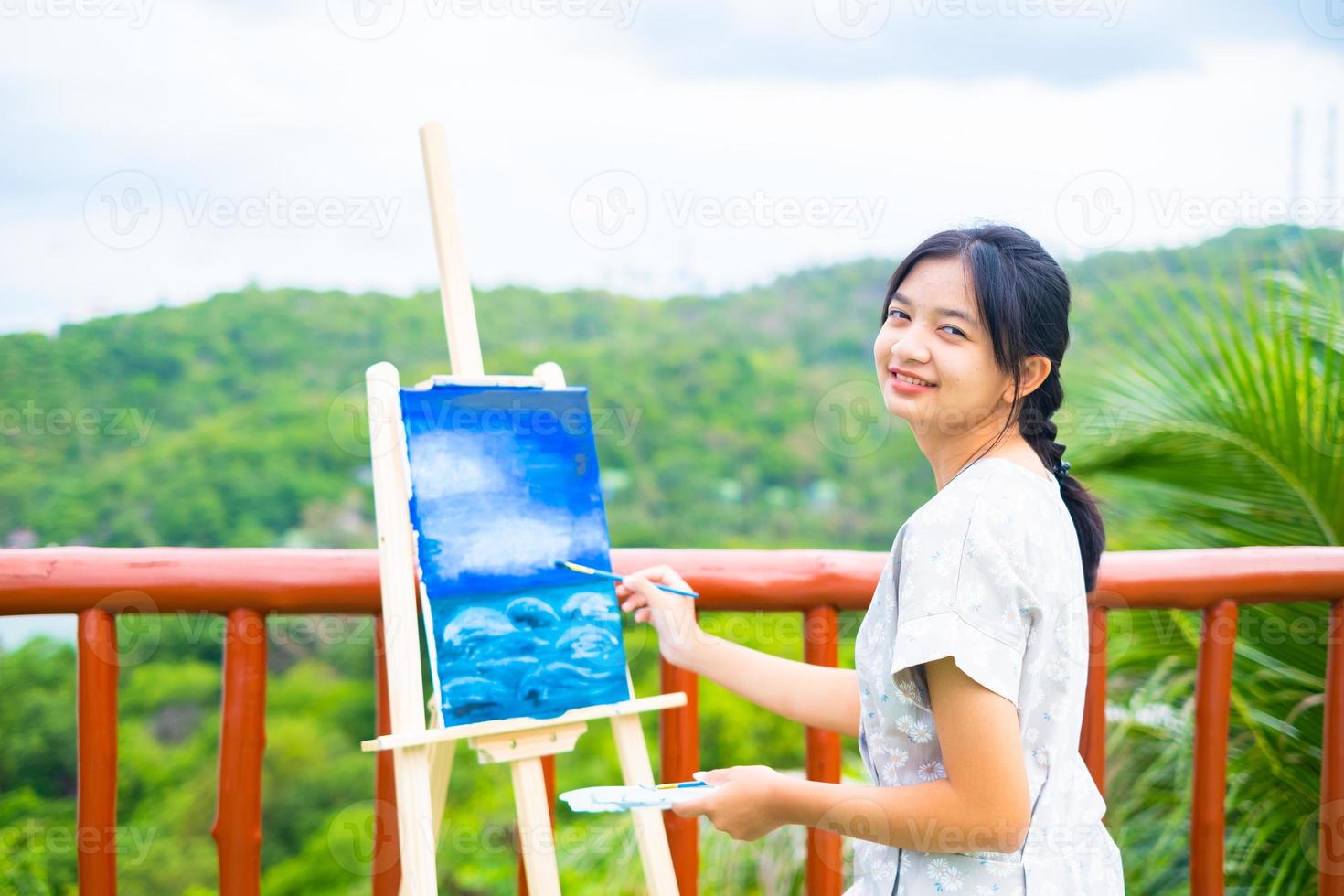 niña usando un dibujo de pincel sobre papel de lienzo, en una hermosa vista del paisaje en koh tao, tailandia. foto