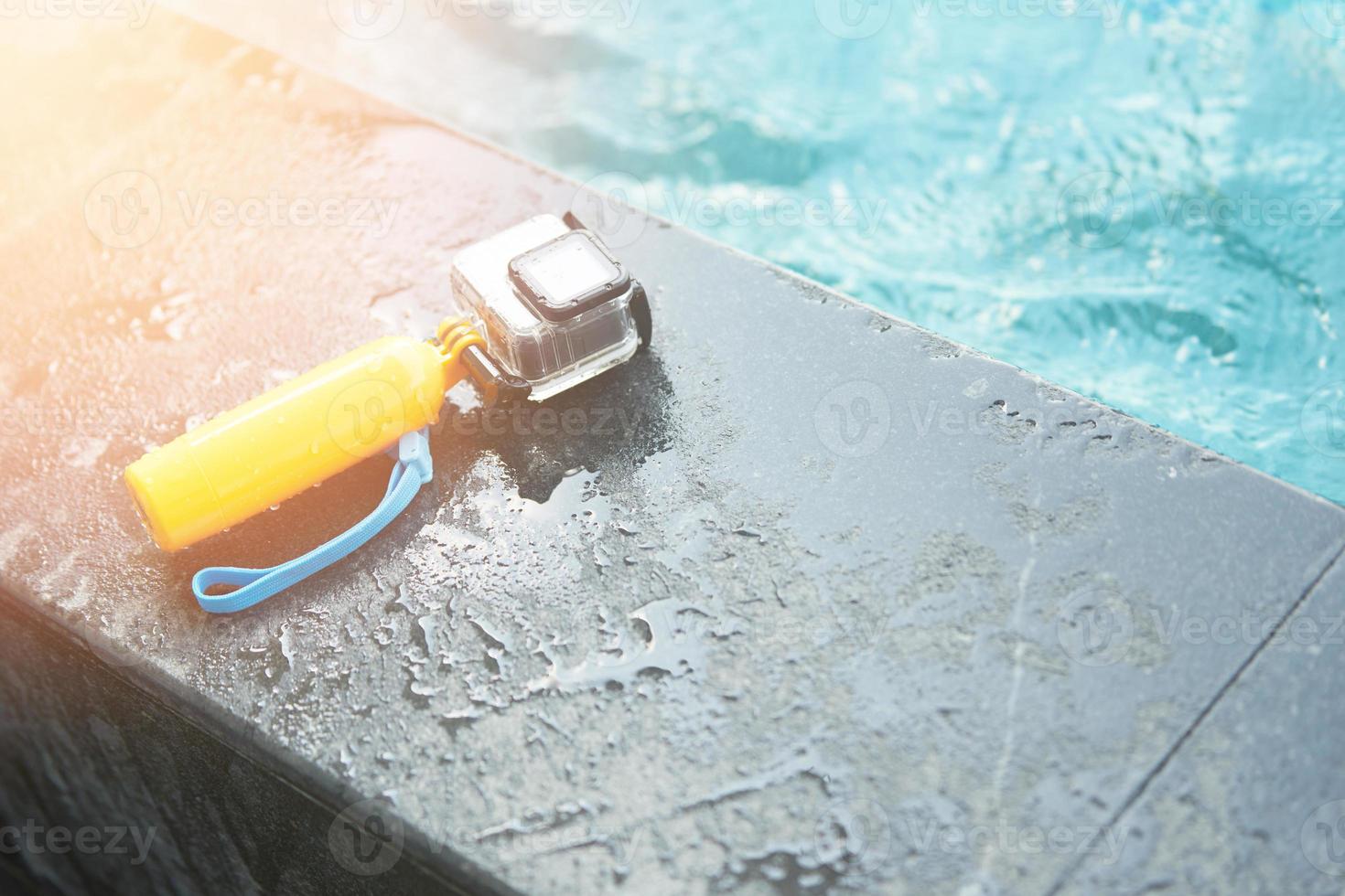 Action camera in water proof case and floating hand grip on pool side photo