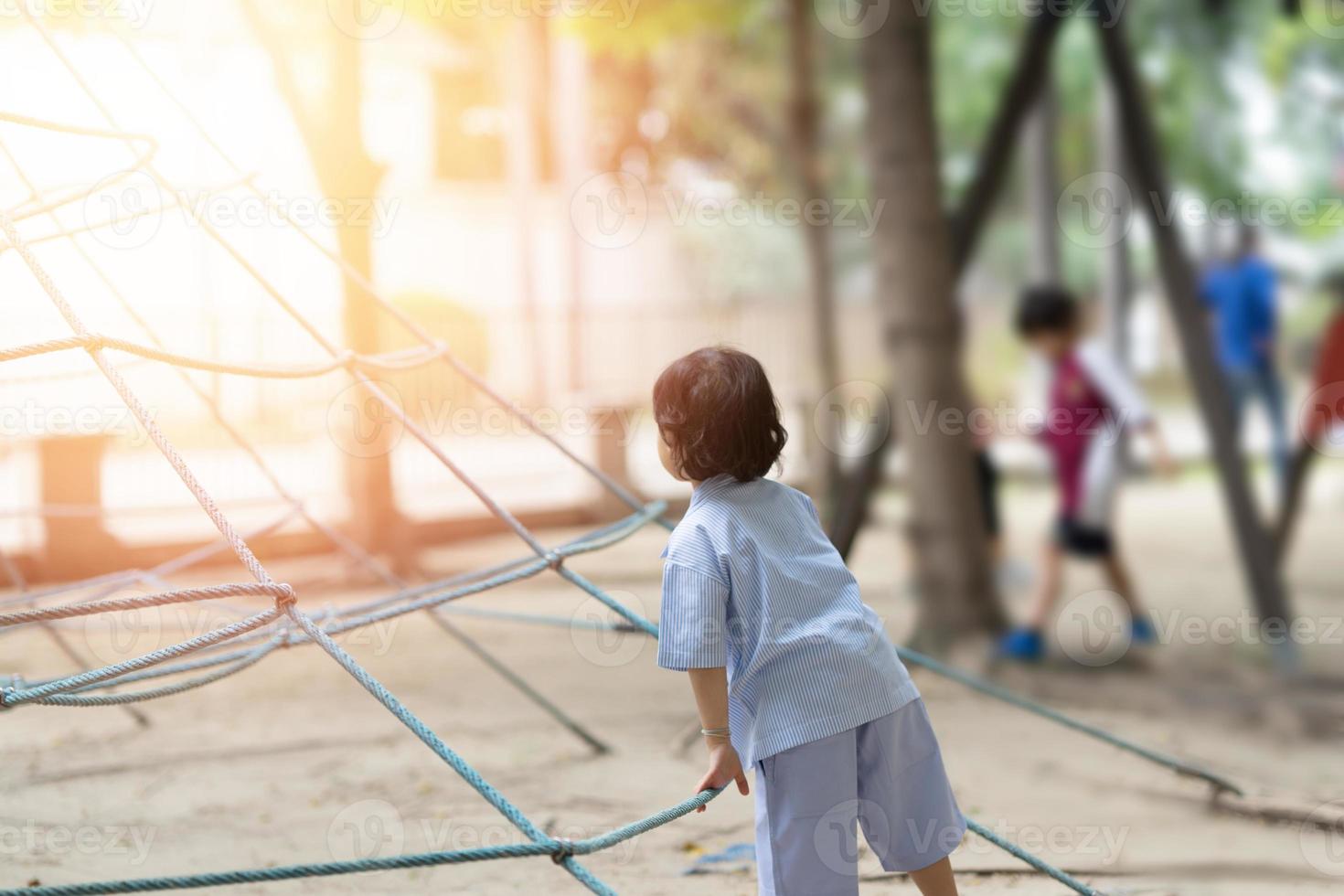bioy kid in uniform play ropr climb in playground photo