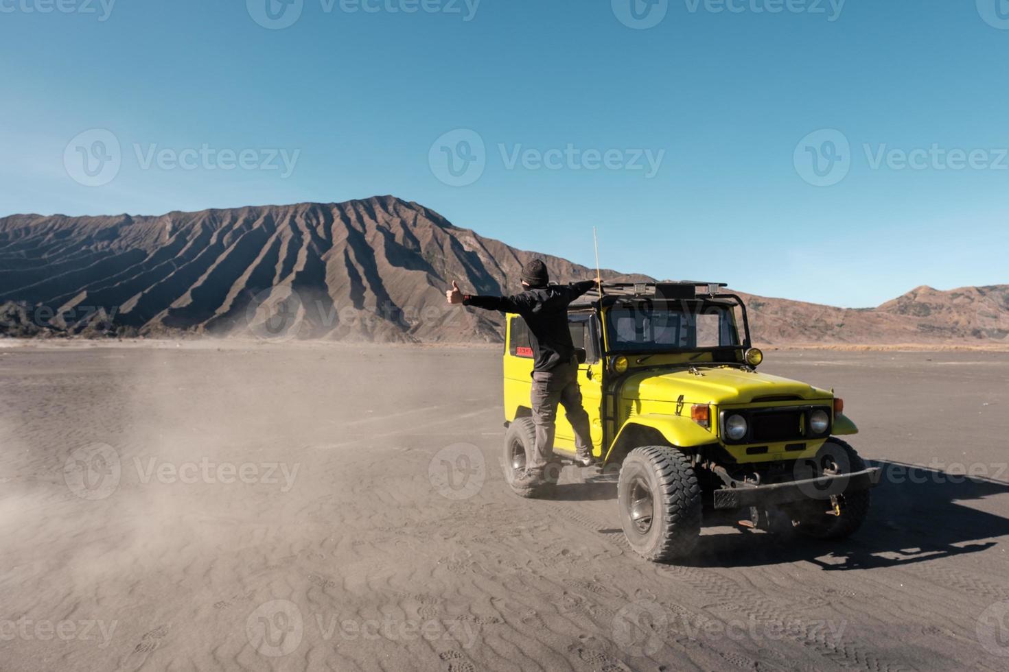 Tourist man thumb a lift on yellow four wheel car in desert photo