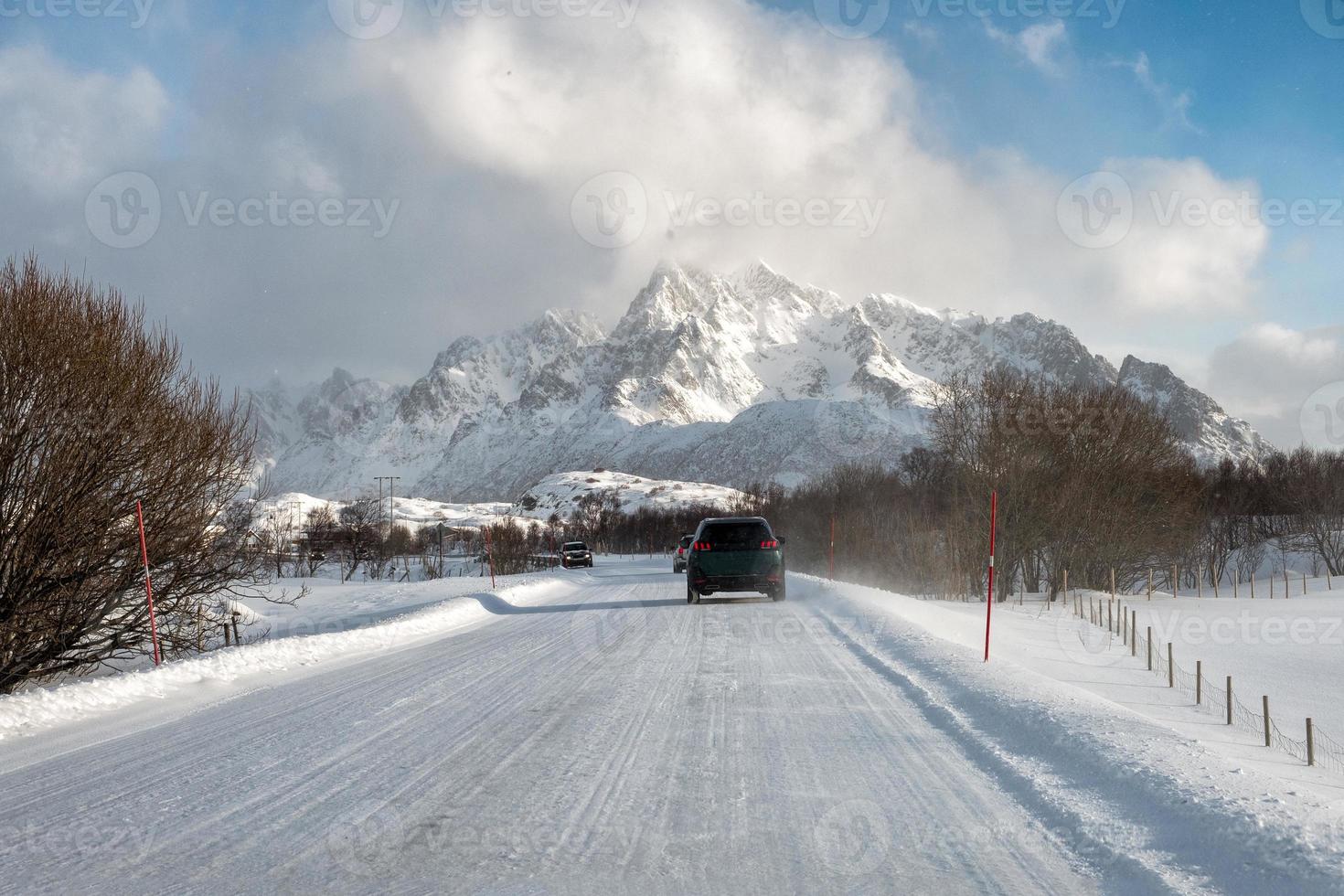 Car driving on snow covered road with mountain in countryside photo