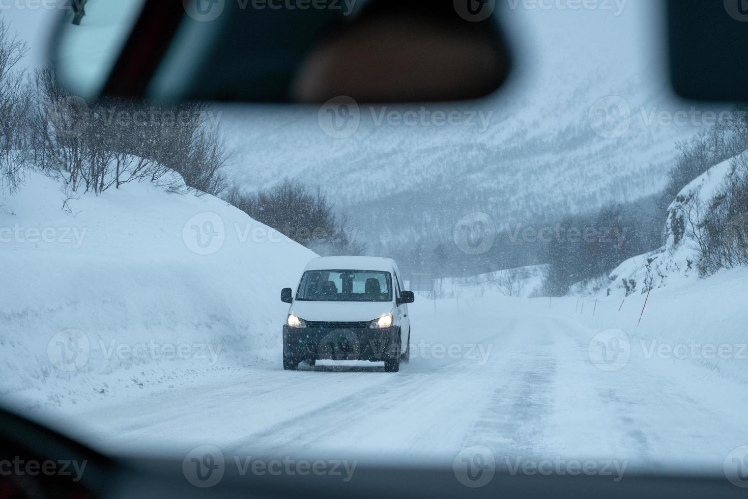 Van driving on highway road with snow covered in blizzard photo