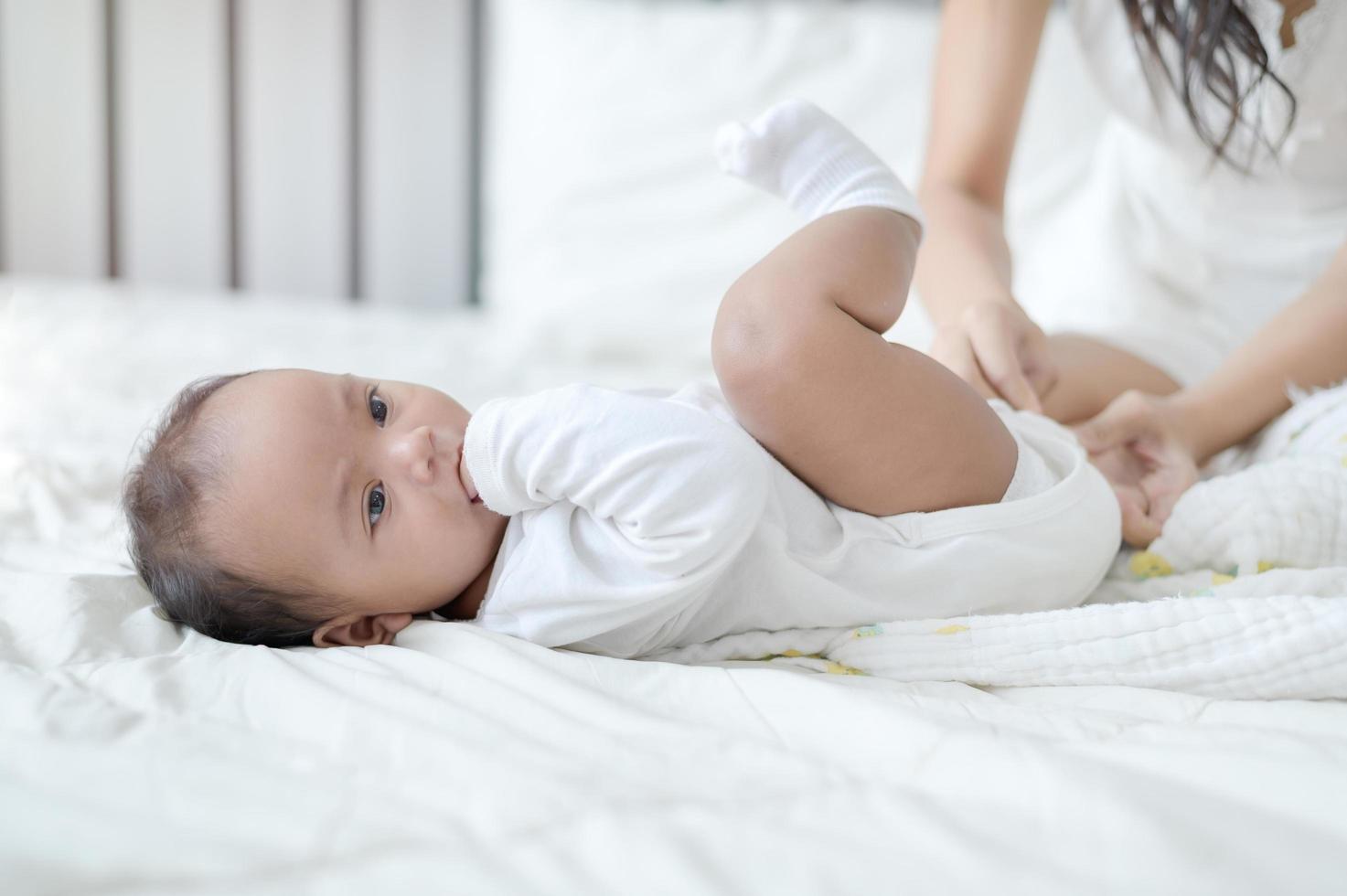 una joven madre asiática está cambiando pañales desechables para su hija recién nacida foto