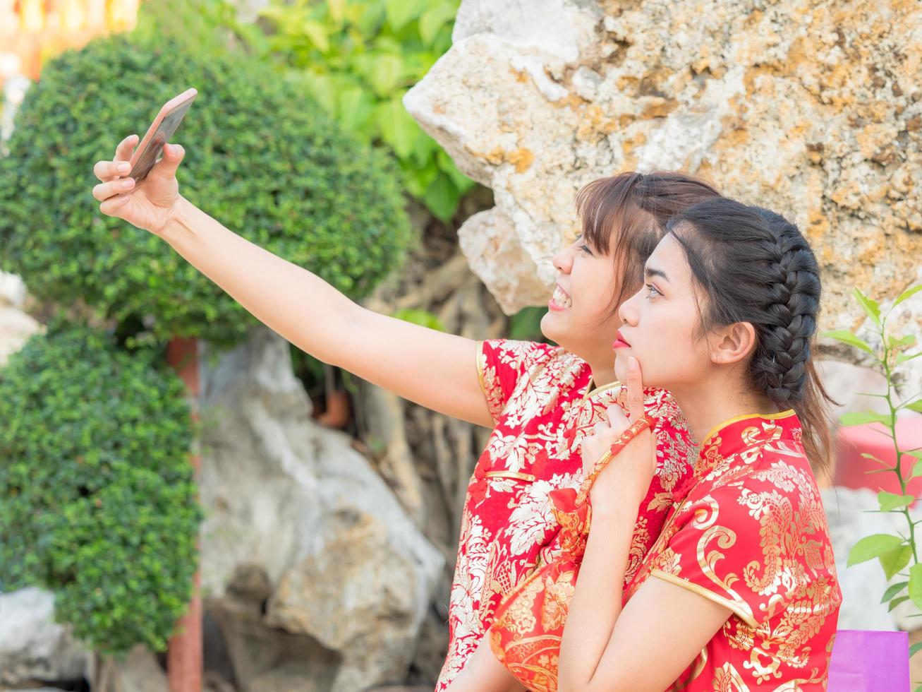 hermosa chica asiática vestida con traje nacional chino está tomando fotos con la cámara desde el teléfono inteligente