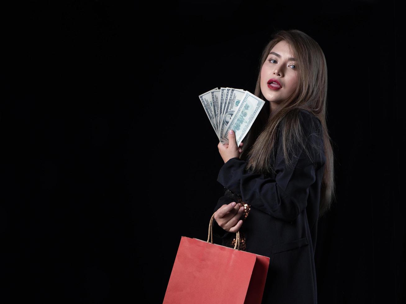 una hermosa mujer asiática con traje negro está feliz después de ir de compras foto