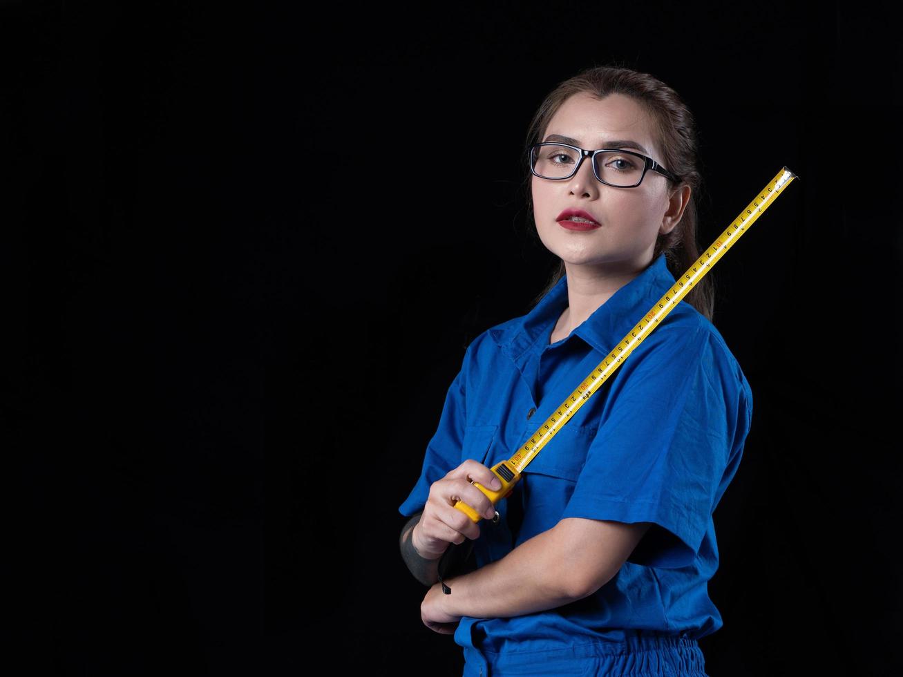 una mujer hermosa con el uniforme técnico azul sosteniendo una herramienta de construcción foto