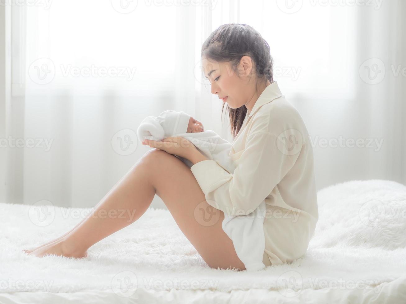 A beautiful Asian woman puts her newborn baby on her body happily and with love photo