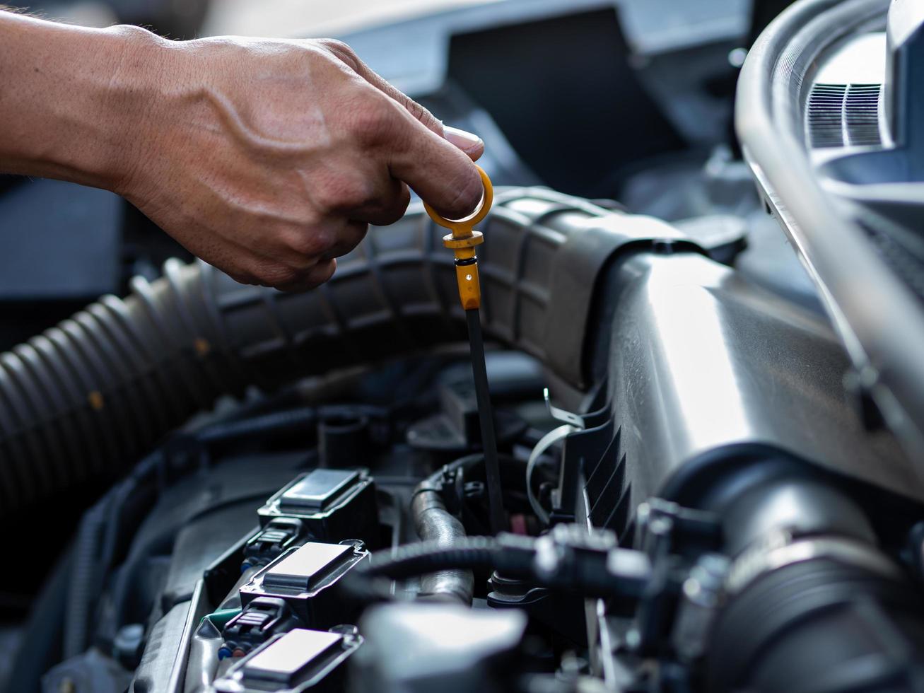 la mano del mecánico está midiendo el nivel de aceite del motor foto