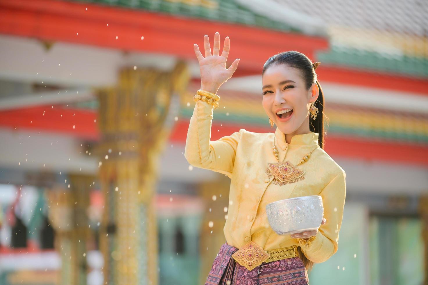 Beautiful Thai girls in Thai costumes hold water bowls and sprinkle water with their hands on Songkran Festival photo