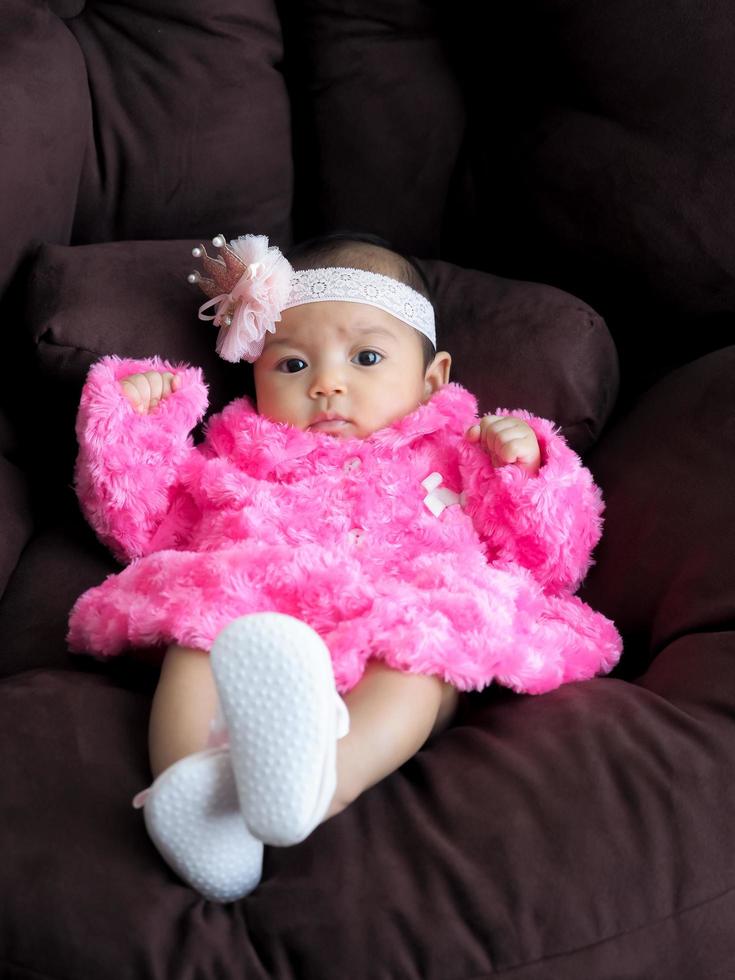 An Asian girl baby wearing a pink shirt lying on the sofa with comfort photo