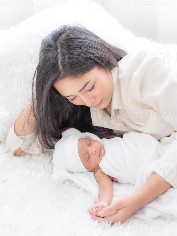 una hermosa mujer asiática abraza felizmente a su bebé recién nacido y la ama foto