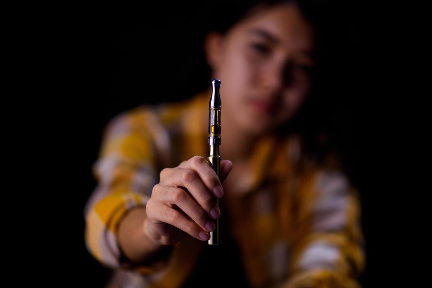 Teenage girl vaporize cannabis through a vaporizer containing cannabis oil in a tube after electrical heating photo