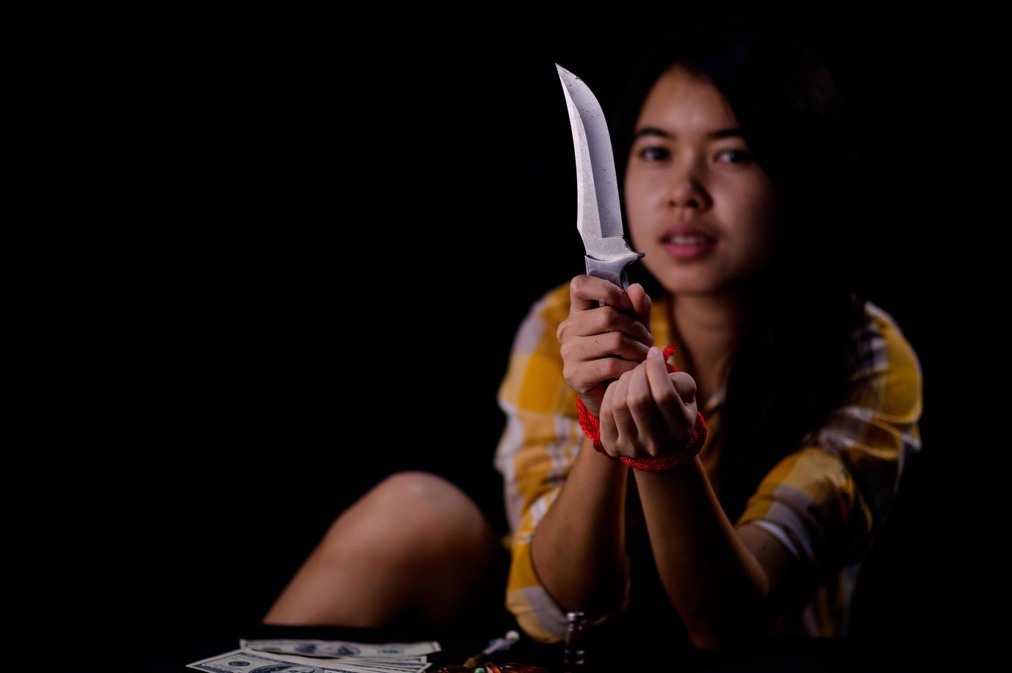 A teenage girl is bound by a rope, stresses and tries to use a knife photo