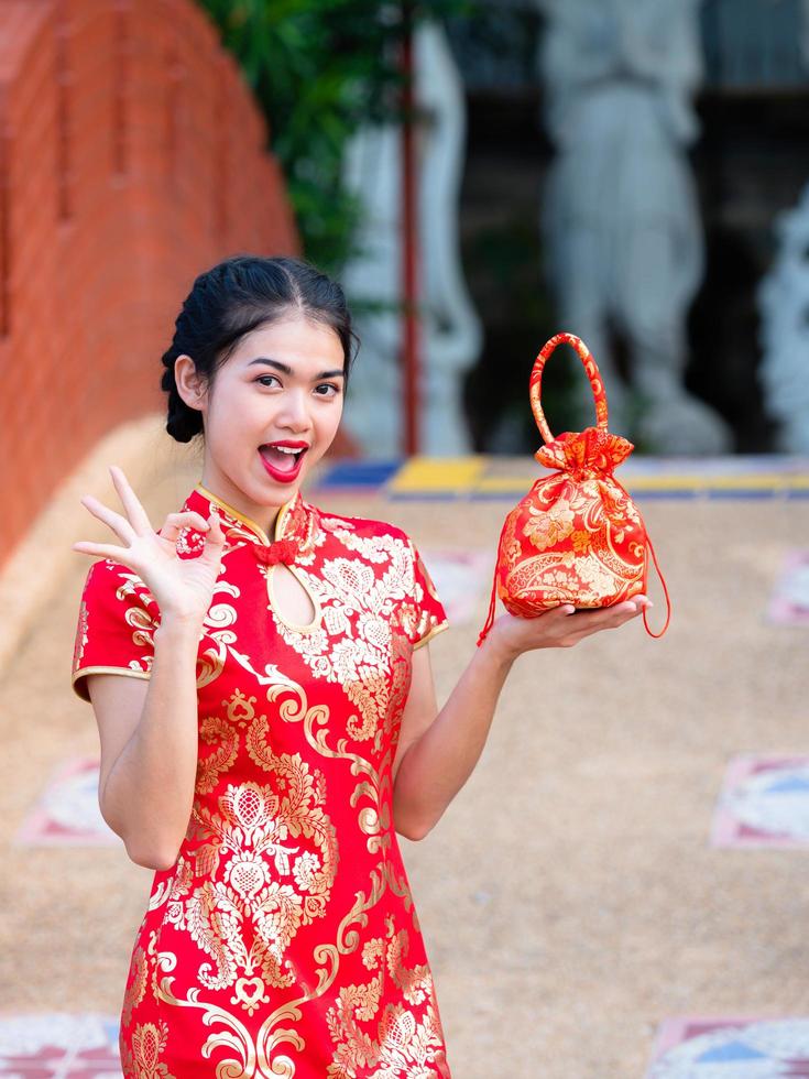 mujeres asiáticas con trajes nacionales chinos sostienen una bolsa de saludo para el evento del año nuevo chino foto
