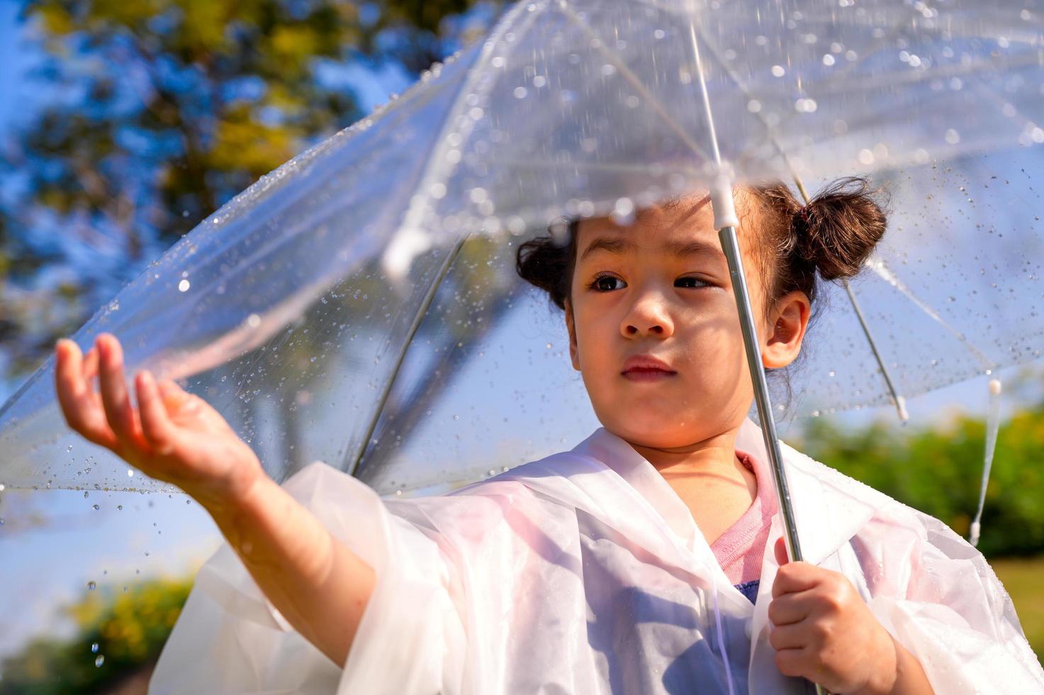 A little girl was happily standing in an umbrella against the rain photo