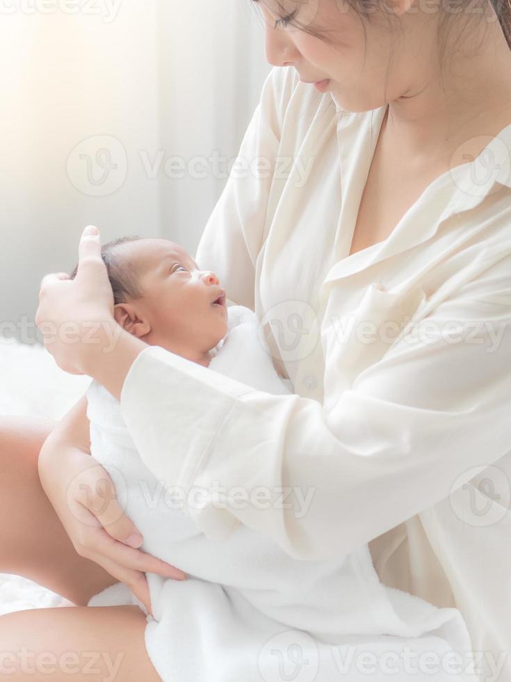 una hermosa mujer asiática pone a su bebé recién nacido en su cuerpo felizmente y con amor foto
