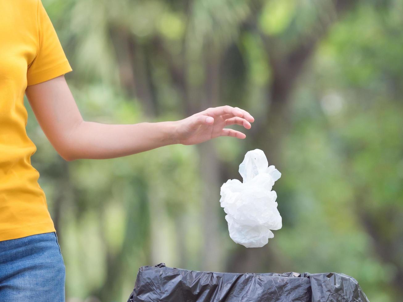 The woman threw a plastic bag after use  into the prepared trash for storage for recycling photo
