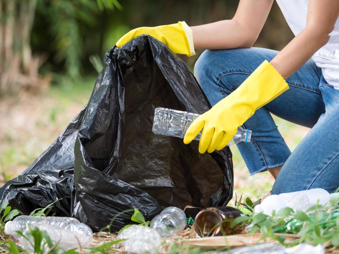 Volunteer women collect plastic water bottles in the park area photo