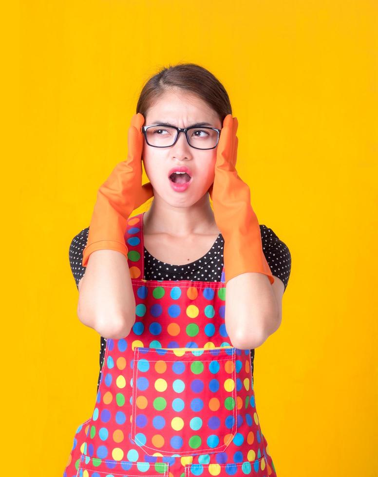 A beautiful Asian woman holds her hand in the head with stress and fatigue in cleaning the house photo