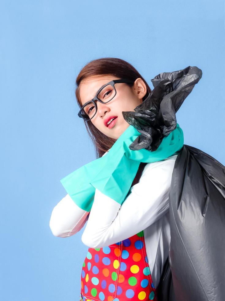 A beautiful Asian woman is carrying a black bag to put the garbage collected with the fatigue of cleaning the house photo