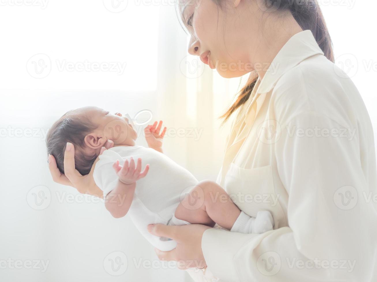 una hermosa mujer asiática pone a su bebé recién nacido en su cuerpo foto
